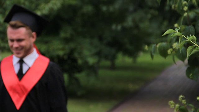 男同学穿着学院装在公园里欢蹦乱跳，毕业了视频素材
