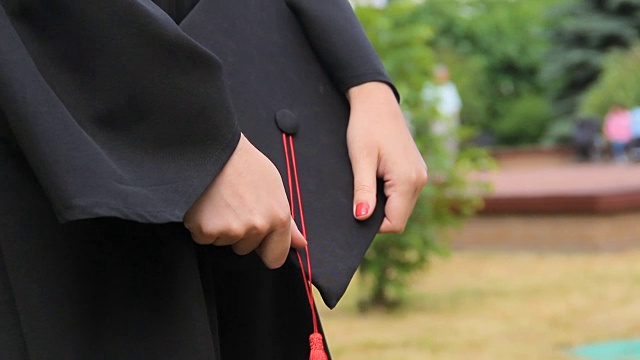 身着学位服的女子手持带有红色流苏的毕业帽，举行典礼视频素材