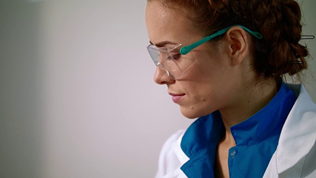 戴着安全眼镜的女科学家。女性科学家脸的特写视频下载