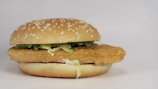 鸡肉汉堡与种子面包和莴苣落在白色的背景视频素材