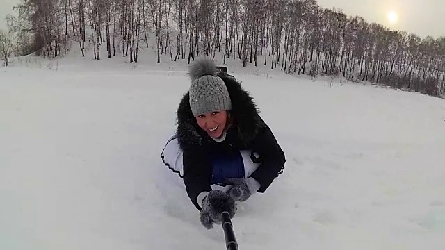 快乐的女孩骑着雪道微笑的雪车。缓慢的运动。雪的冬天的风景。在户外运动视频下载