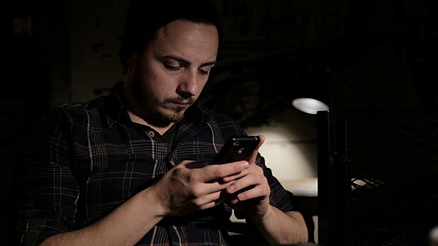 年轻人晚上在咖啡馆用智能手机发短信视频下载