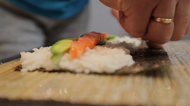 手做长寿司卷。米饭配鱼片。寿司师傅展示厨艺。著名的日本菜。视频素材