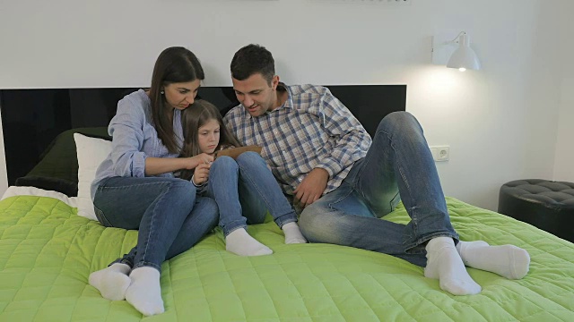 妈妈微笑着，爸爸和女儿躺在床上视频下载