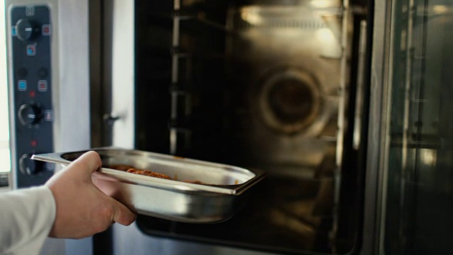专业厨师把肉放进餐厅厨房的烤箱的特写镜头视频素材