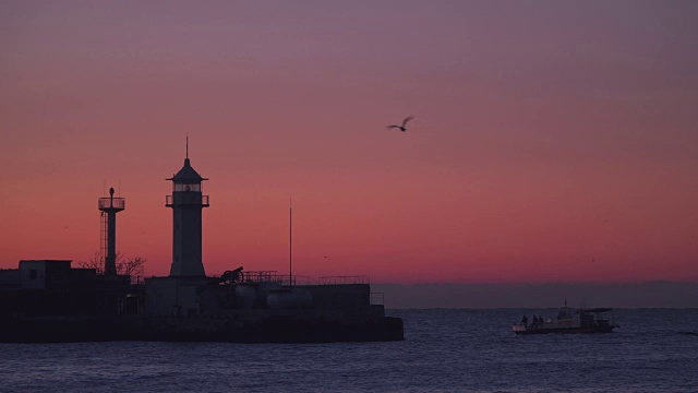 日出时渔船在灯塔附近游泳视频素材