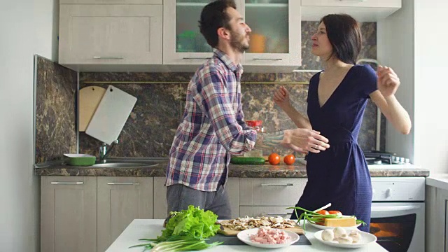 幸福美丽的夫妇在厨房做饭的时候跳舞和接吻视频素材