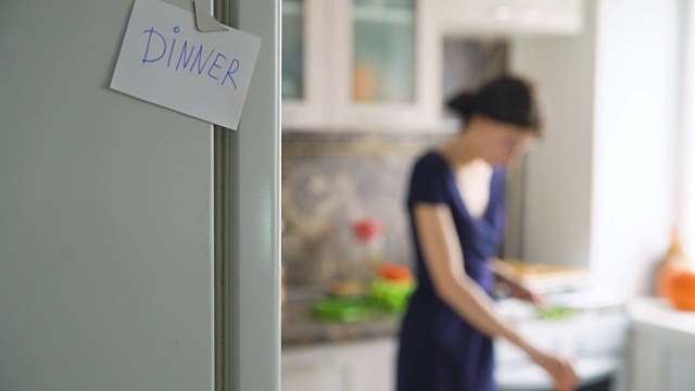 晚餐纸上模糊背景的女人在厨房里做饭视频素材