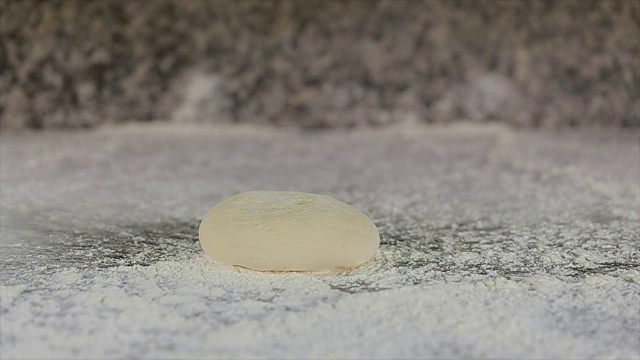 生面团落在撒了面粉的桌子上。视频下载