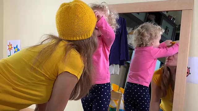 女人和女孩把帽子戴在镜子旁边视频素材
