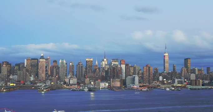 从白天到晚上，曼哈顿中城上空的云与哈德逊河上的船在前景视频素材