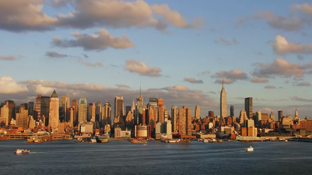 时间流逝广域网拍摄的云在曼哈顿中城天际线日落与船在哈德逊河在前景视频素材