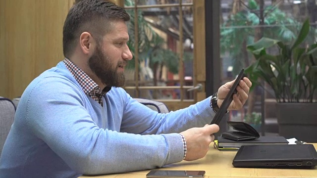 男子在咖啡厅用平板电脑打视频电话，用镜头拍摄视频下载