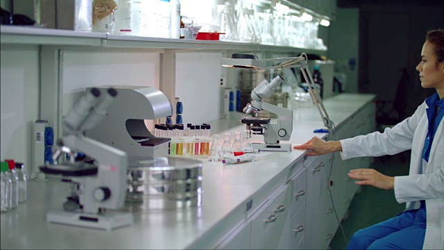 女科学家开始使用显微镜。微生物学家观察显微镜视频下载