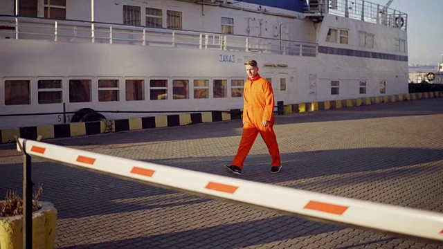 穿着橙色制服的码头工人走过港口的护栏视频素材