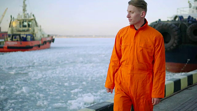 冬天，码头工人穿着橙色制服，看着大海，走在港口里。冰的海洋视频素材