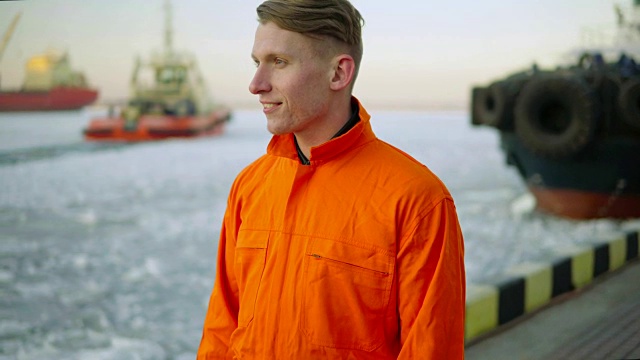 冬天，码头工人穿着橙色制服望着大海，欣赏着港口的风景。冰的海洋视频素材