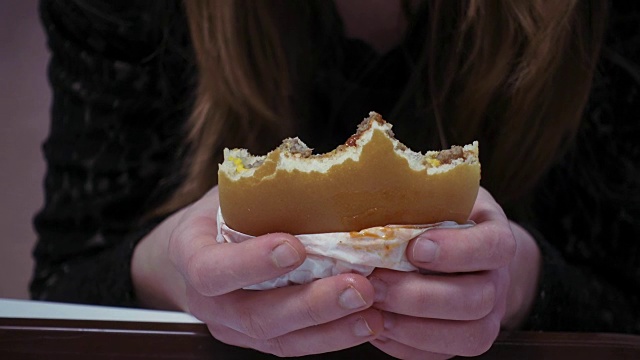年轻女子正在吃汉堡包和炸薯条视频素材