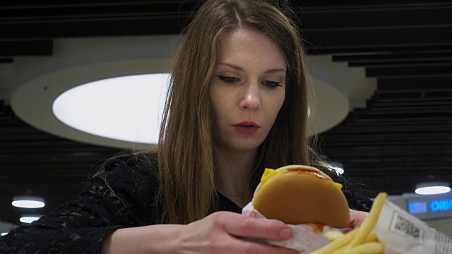 年轻女子在快餐店拆汉堡包的包装纸视频素材