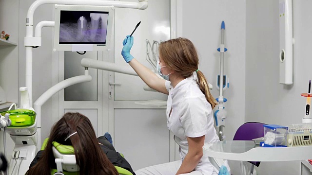 牙齿健康和牙齿保健。自信的专业牙医正在平板电脑上展示x光牙齿。女牙医戴着面具，穿着实验服。视频素材