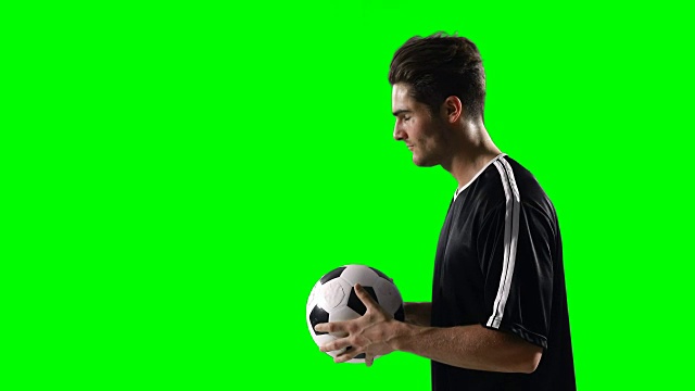 对着绿色屏幕举着足球的足球运动员视频素材