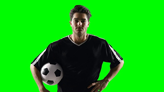 对着绿色屏幕举着足球的足球运动员视频素材