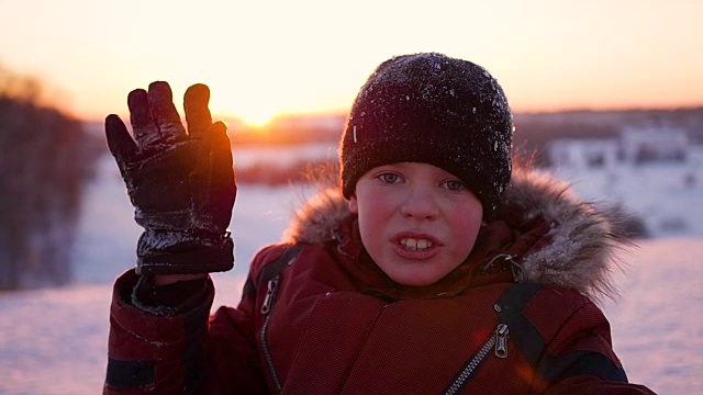 一个孩子在冬日公园挥手，夕阳的背景视频下载