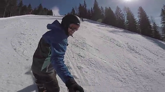 冬天在阿尔卑斯山滑雪。一个男人在滑雪板上滚动，在一个滑雪胜地积雪覆盖的小径上。那家伙在一个极限摄像机前离开了视频素材