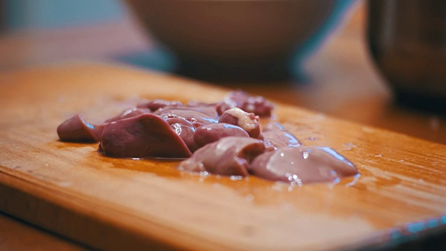 女厨师在家庭厨房的木板上切鸡肝肉视频下载