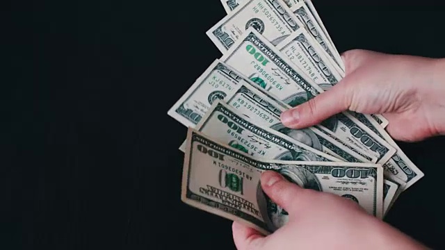 女人的手捧着一把百元大钞并数着视频素材