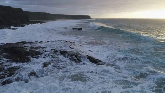 无人机拍摄的日落时的海浪和山脉视频素材