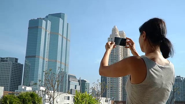女人用手机拍下城市的照片。视频素材