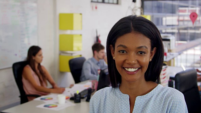 办公室里的一名年轻黑人女性走进焦点，面带微笑视频素材