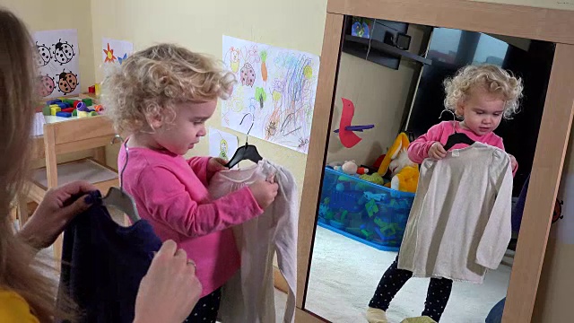妈妈和她的小女儿在镜子前量衣服视频素材