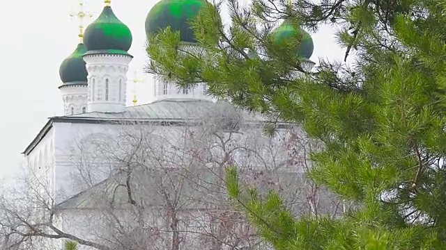 俄罗斯克林姆林宫阿斯特拉罕的老俄罗斯东正教教堂，在冬天透过常青的树枝看视频下载