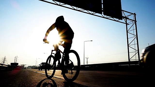 在交通繁忙的高速公路上骑自行车的人的剪影，慢镜头视频下载