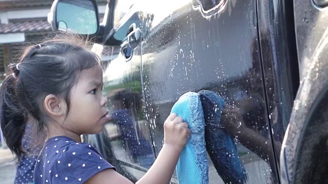 亚洲小女孩和家人一起洗车，慢镜头拍摄视频素材