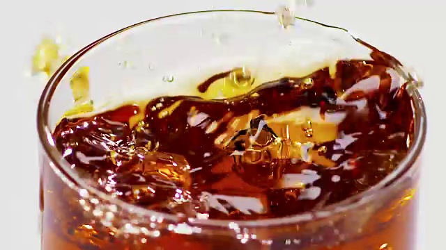 两块冰块掉进了装有威士忌的玻璃杯里。慢动作视频素材