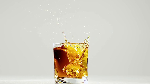 两块冰块掉进波旁威士忌酒杯里。慢动作视频素材