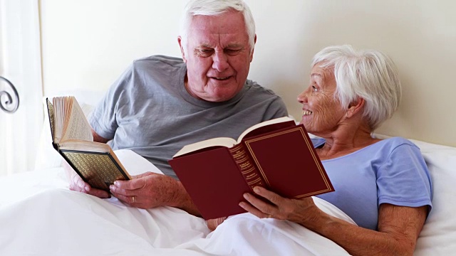 一对快乐的老年夫妇在床上看书视频素材