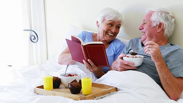 老年夫妇在床上吃早餐时互相互动视频素材