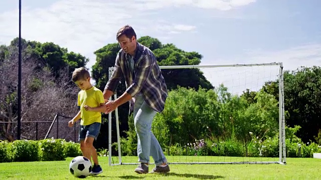 父亲协助儿子踢足球视频素材
