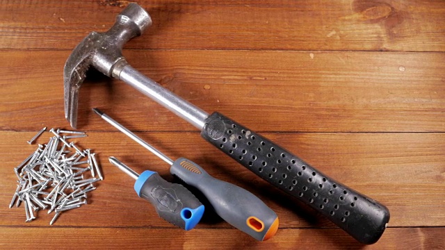 木匠的工具放在一张木桌上。锤子、螺丝刀、钉子。用木头工作的概念视频下载
