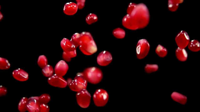 成熟的红石榴子在黑色背景上飞舞视频素材