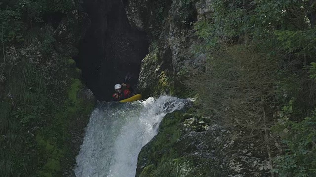 慢动作:运动员划着独木舟穿过汹涌的白水瀑布视频素材
