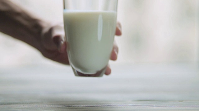 手把一杯牛奶放在木桌上视频素材