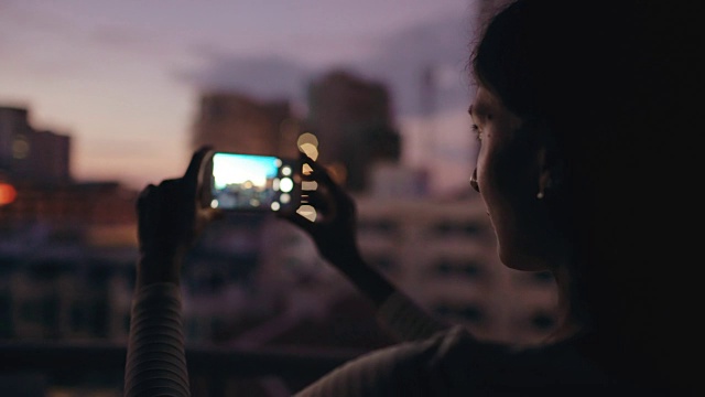 女人在酒吧屋顶露台上用智能手机拍摄城市景观的特写视频下载