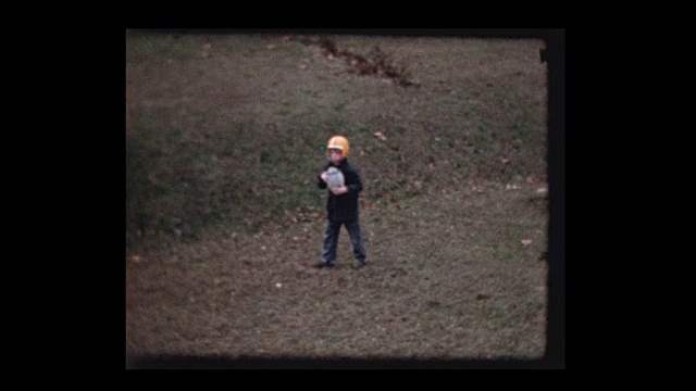 小男孩戴着橄榄球头盔在后院踢足球视频素材