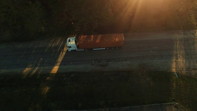 航拍一辆货柜车行驶在阳光明媚的乡村公路上。视频素材