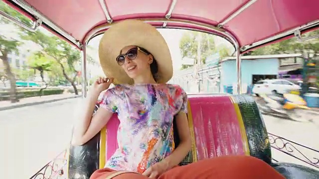 年轻漂亮的女游客戴着帽子在泰国曼谷乘坐传统的泰国巴士songteo视频素材